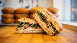Photo of an Ideal's sandwich cut and sitting on a cutting board.