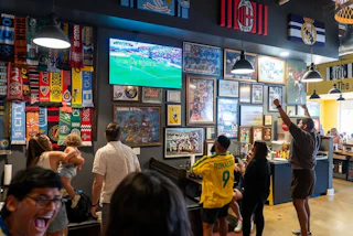 People cheer as they watch a soccer game inside The Boot Room. The Boot Room is a sandwich shop, soccer pub and event space, located next to Beer Study and Starpoint Brewing in the Rockwood neighborhood in Durham.