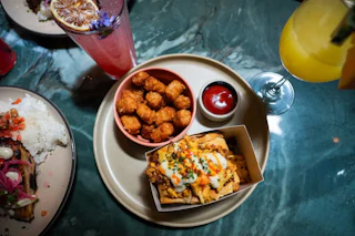 A table full of drinks and food at Aaktun Coffee + Bar, a dual-concept destination with a stylish daytime café and an intimate, Tulum-inspired dining room.