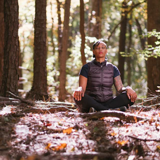 Photo of a person meditating in a forest in Durham, NC. There are many ways to have a week of wellness in the Bull City from walking or running outdoors to saunas and spas.