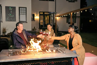 People toast glasses of wine over the fire pit behind Morehead Manor.