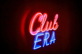 Neon Club ERA sign lights up the dark room.