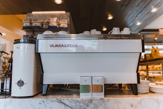 Two bags of Counter Culture Coffee sit in front of an espresso machine at Mad Hatter Cafe + Bakeshop in Durham, NC.