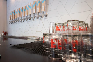 Branded glasses are stacked next to a line of beer taps, waiting to be filled at Fullsteam Brewery in Durham, NC.
