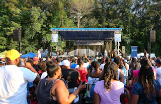 Many Bimbé festival goers gather in front of a stage enjoying live music.