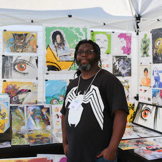 An artist stands in front of paintings for sale at Centerfest in Durham, NC.