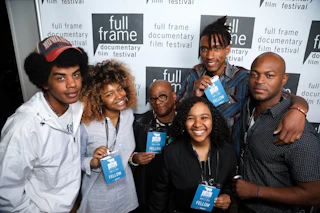 A group of fellows showing off their lanyards in front of a step and repeat for Full Frame Documentary Film Festival