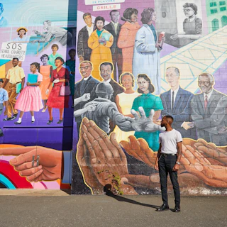 A man stands in front of one of Durham's Black history murals.
