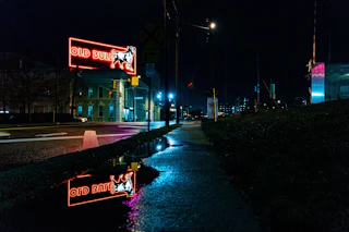 The streets of Durham are lit up at night by the neon Old Bull sign downtown after a rainy evening.