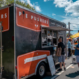 Customers line up at the Pie Pushers food truck waiting for pizza.
