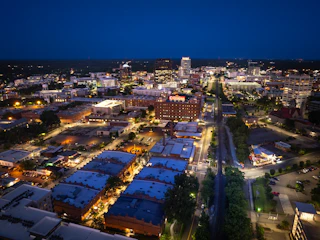 An aerial photo shows the Durham night skyline over the Brightleaf District.