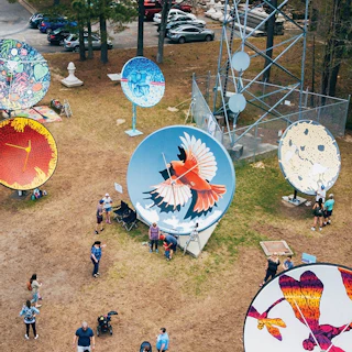 image of park with people looking at old satellite dishes that have been painted like murals