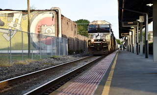 A train passes through the Durham Amtrak station on a sunny day.